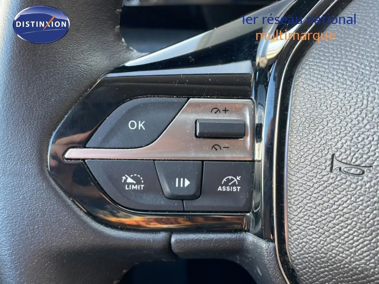 Gros plan sur les commandes au volant à gauche de la Peugeot 308 2024, boutons de régulateur et d'assistance visibles.