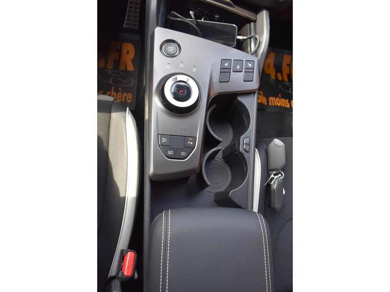 Vue plongeante sur la console centrale du Kia Sportage noir 2026, avec molette de boîte auto et porte-gobelets.