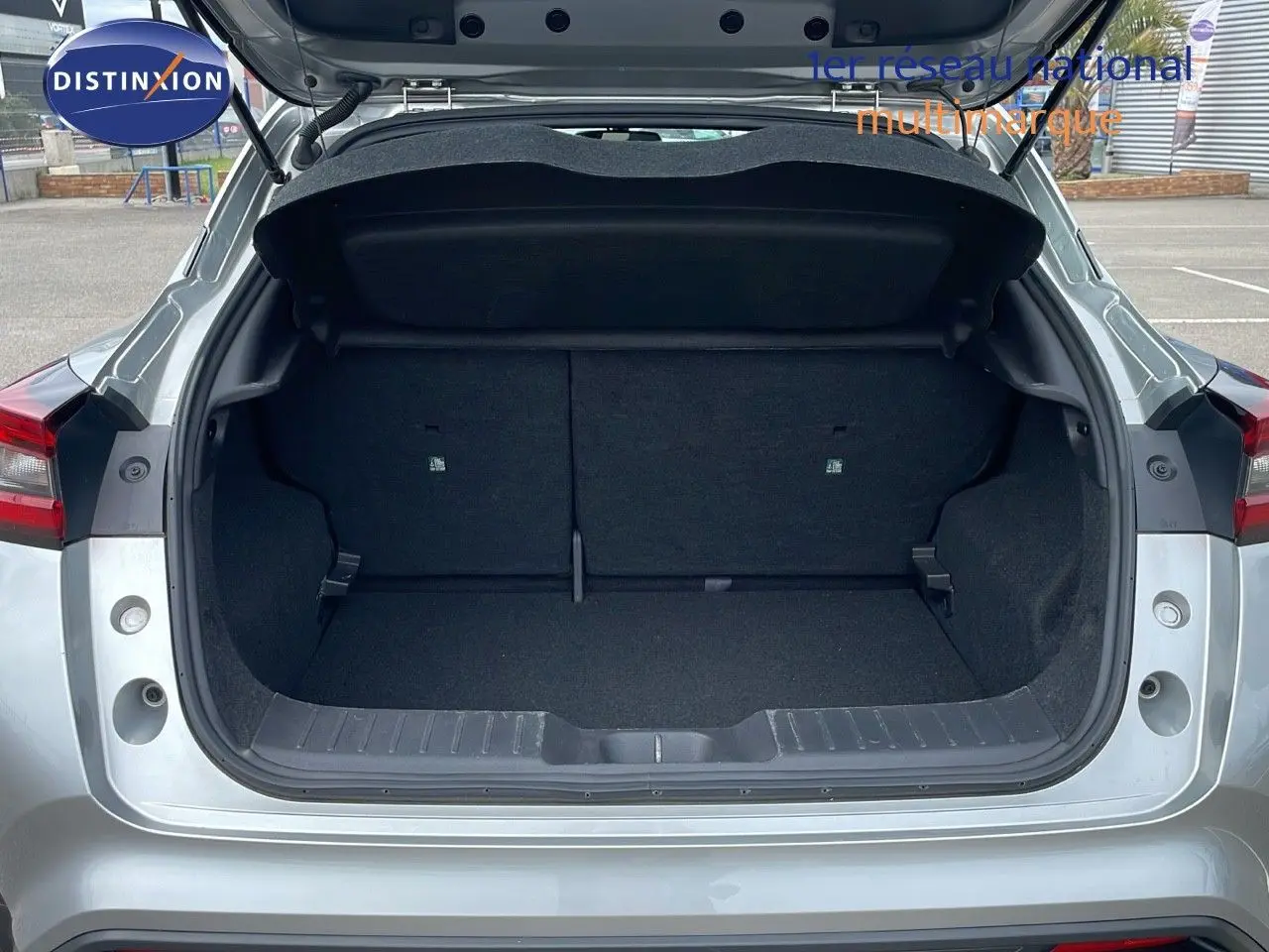 Coffre ouvert d'un Nissan Juke gris perle métal 2023, vue arrière montrant l'espace de chargement vide.