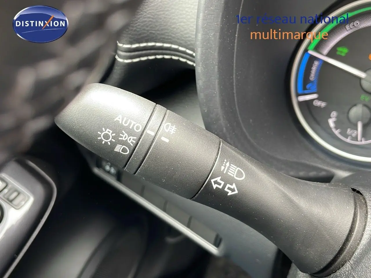 Gros plan sur la commande des feux et clignotants du tableau de bord d'un Nissan Juke gris perle hybride 2023.