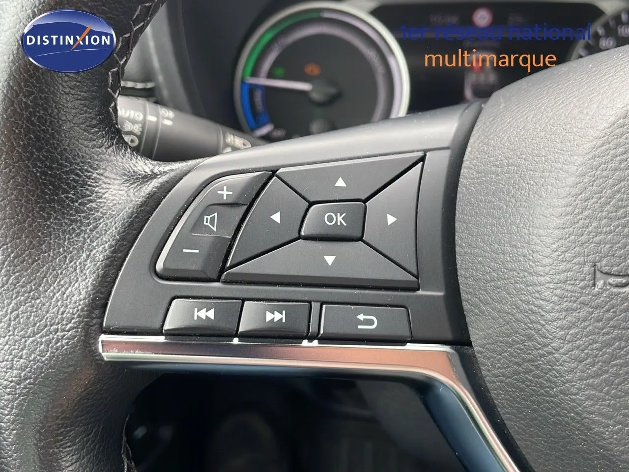 Gros plan sur les commandes à gauche du volant en cuir noir du Nissan Juke hybride 2023, tableau de bord en arrière-plan.