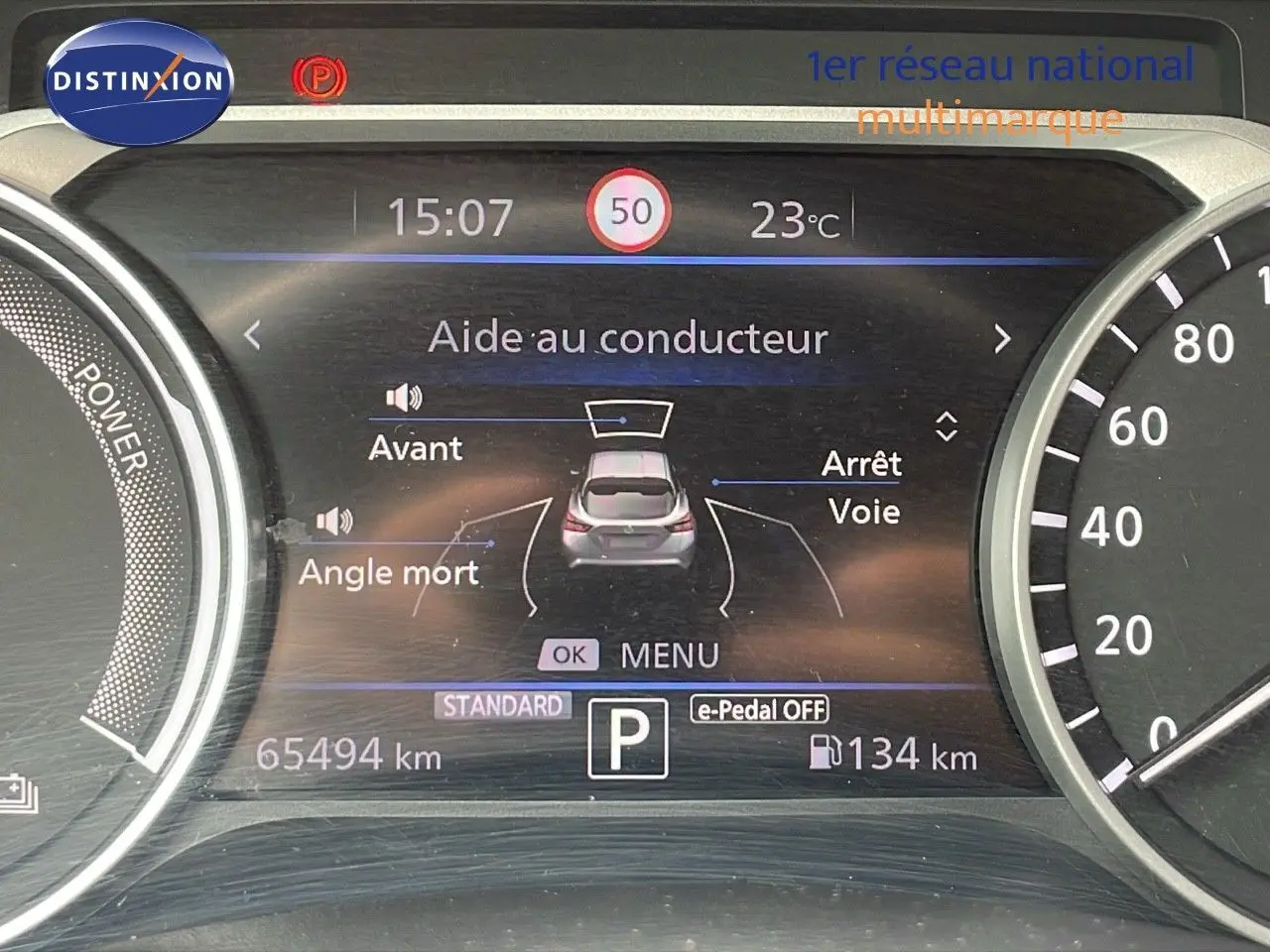 Tableau de bord numérique du Nissan Juke gris perle, affichant l'aide au conducteur et la vitesse à 15h07.