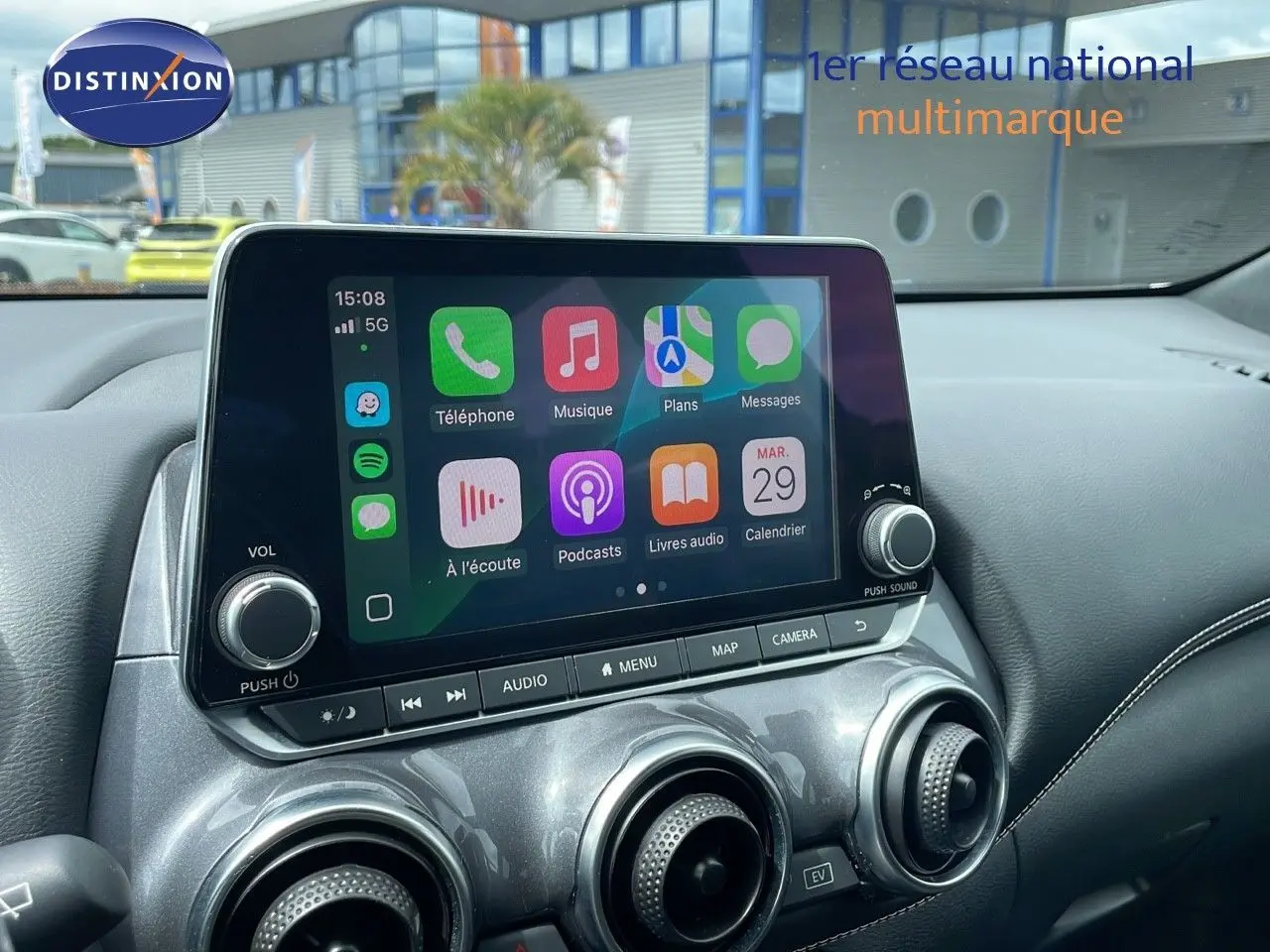 Écran tactile central avec interface connectée dans l'habitacle du Nissan Juke Hybrid gris perle métal, vue intérieure avant.