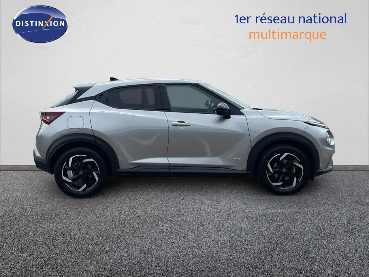 Profil droit d'un Nissan Juke Hybrid 143ch Business+ gris perle métal avec jantes noires et détails noirs contrastants.