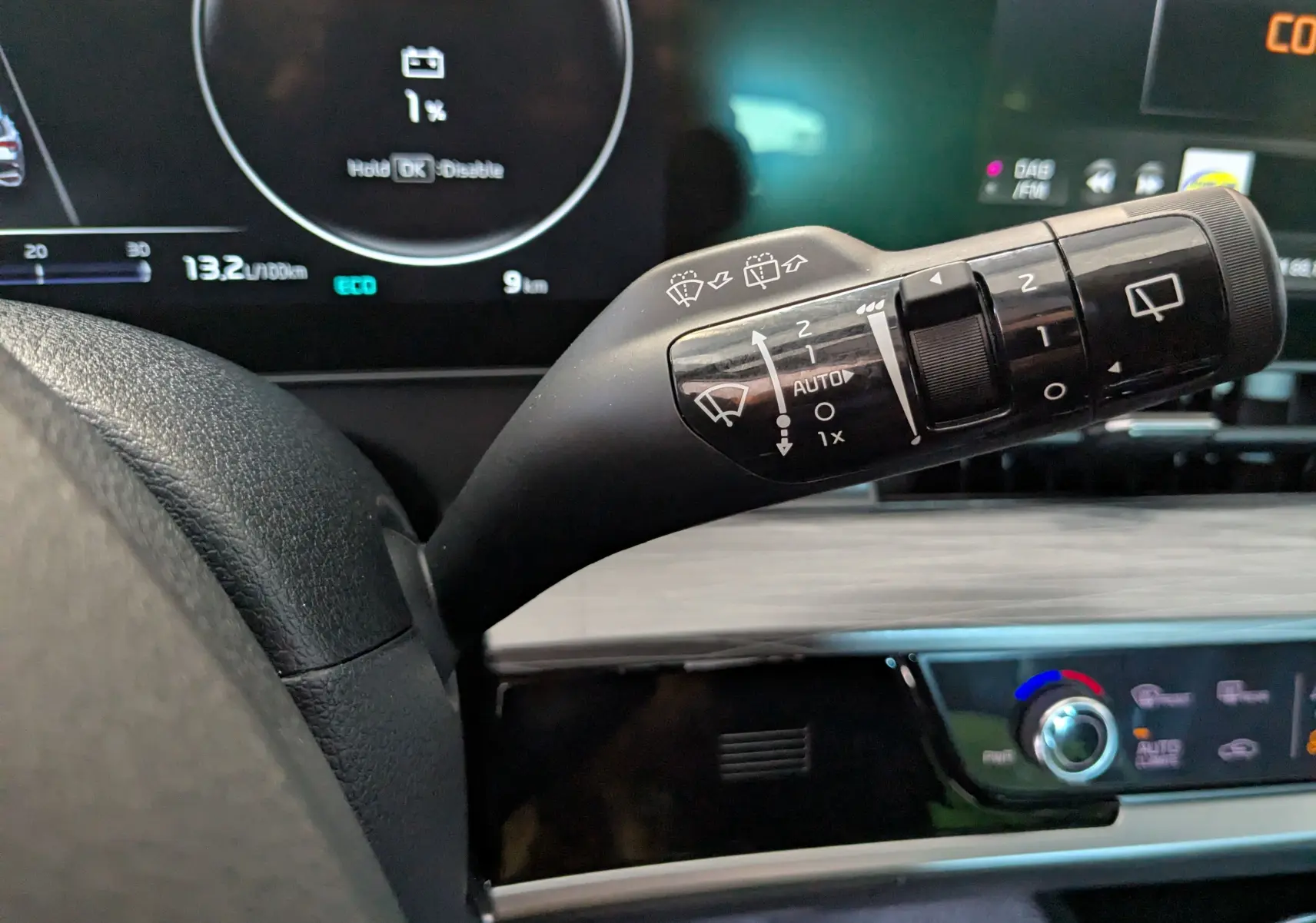 Gros plan sur la manette d'essuie-glace du Kia Sportage blanc 2025, avec tableau de bord numérique en arrière-plan.