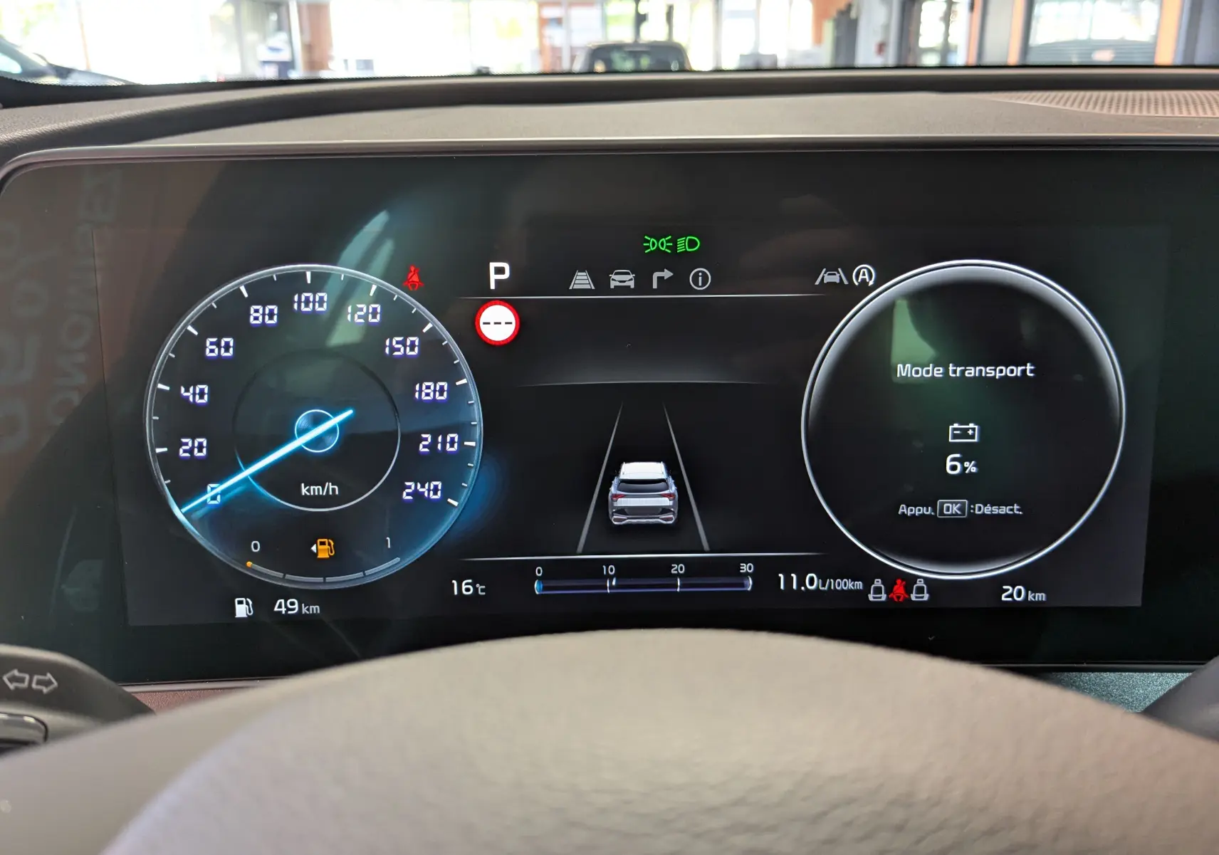 Tableau de bord numérique du Kia Sportage blanc MY25, affichant la vitesse, mode transport et alertes au centre.