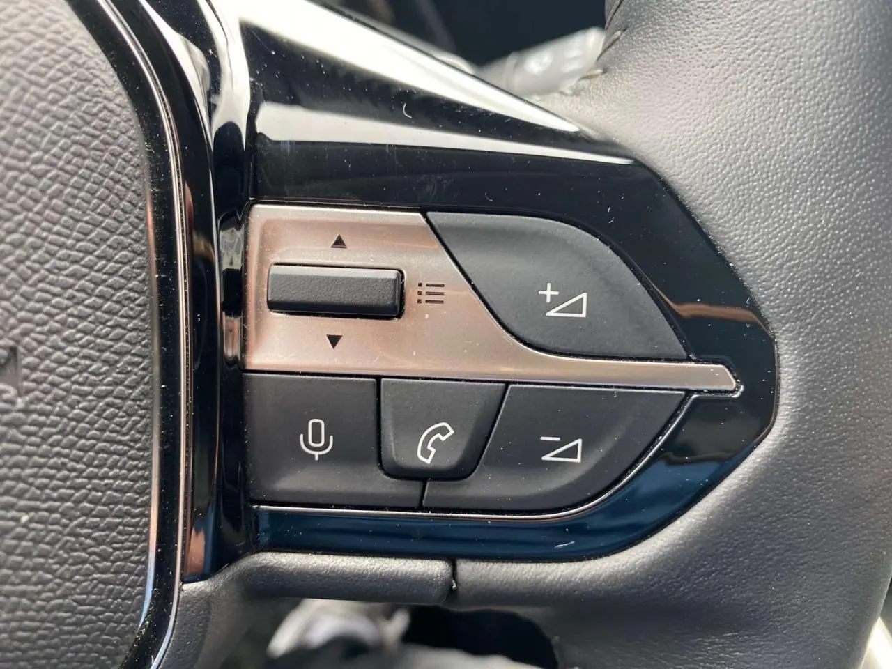 Gros plan sur les commandes noires du volant de la Peugeot 308 2023, finition Allure Pack, intérieur noir.