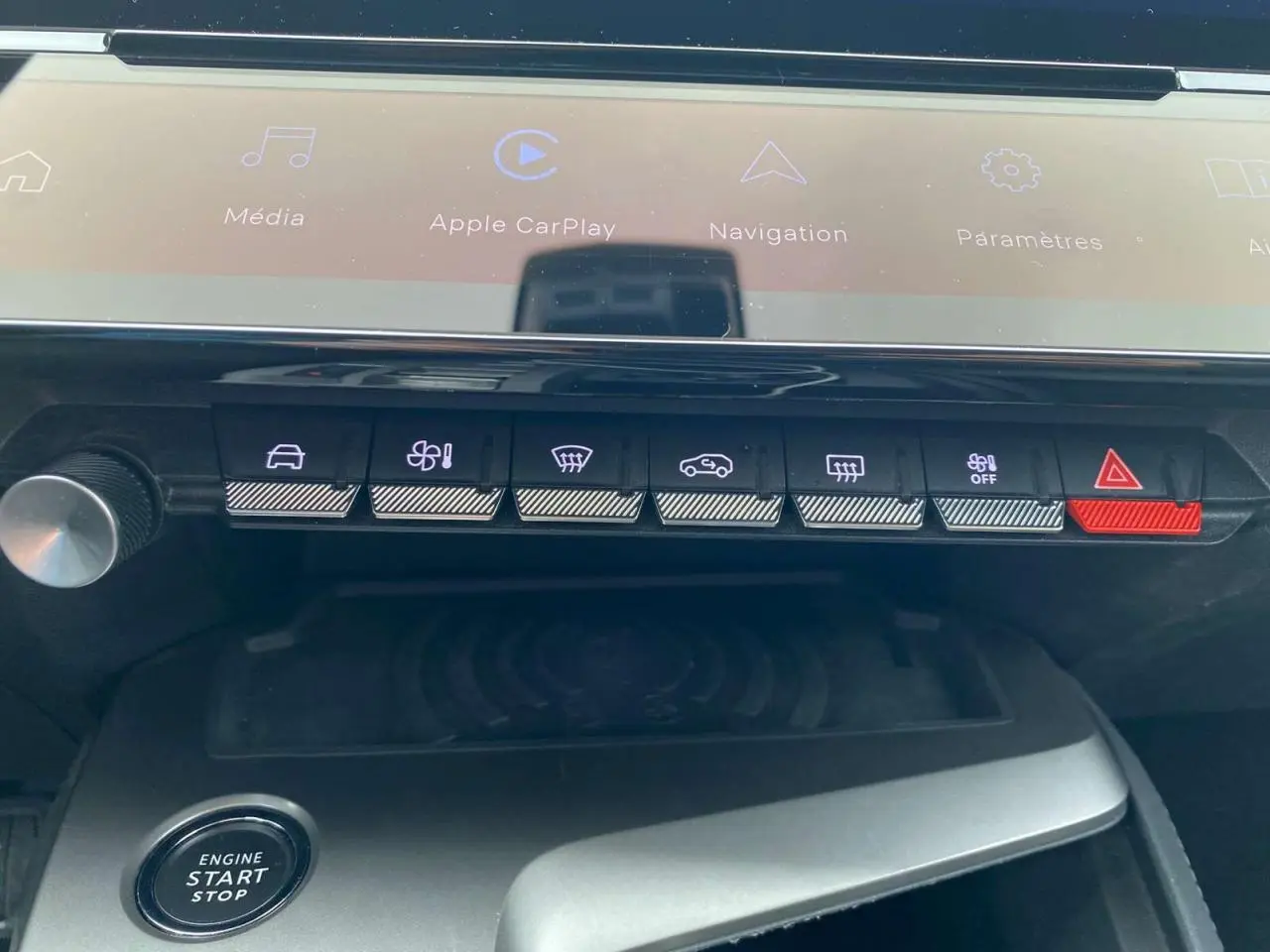 Gros plan sur la console centrale de la Peugeot 308 2023 avec commandes tactiles et chargeur induction visible.