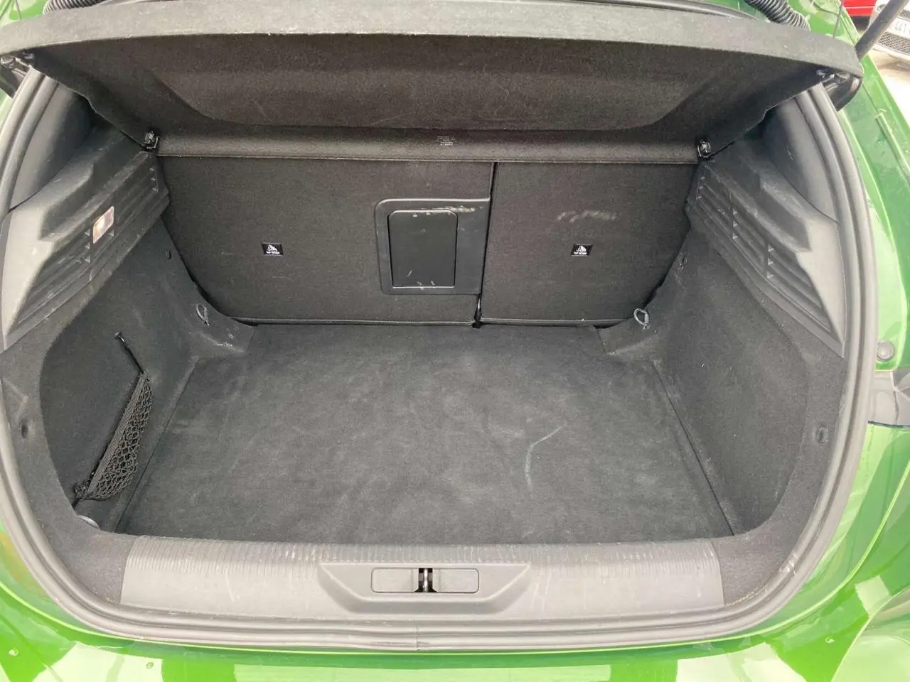 Coffre ouvert vu de l'arrière d'une Peugeot 308 2023 vert olivine, montrant un espace de chargement propre et spacieux.