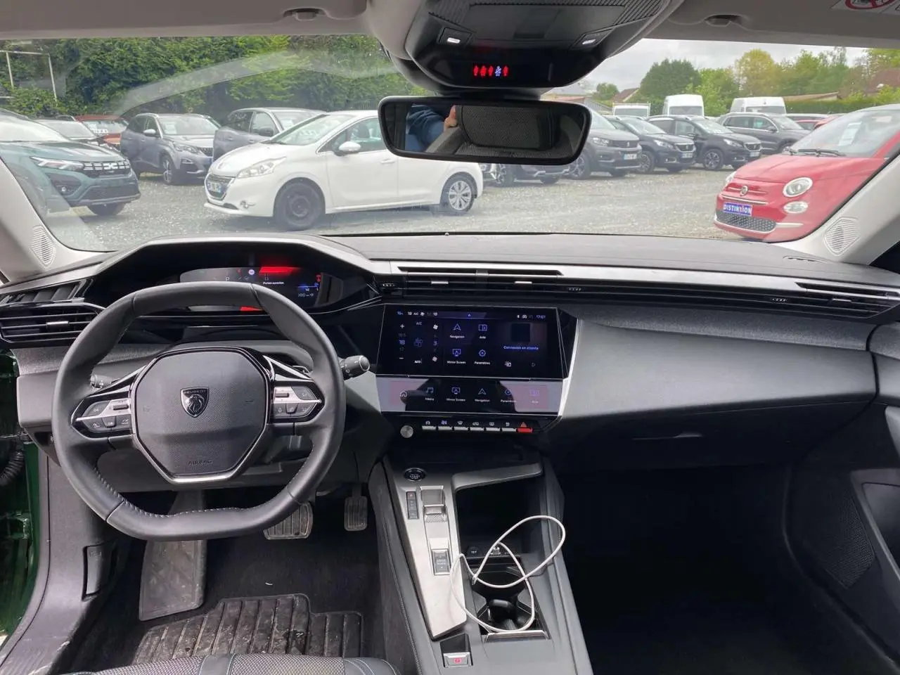 Intérieur de la Peugeot 308 2023 vue de face, tableau de bord noir avec écran tactile central et volant compact.