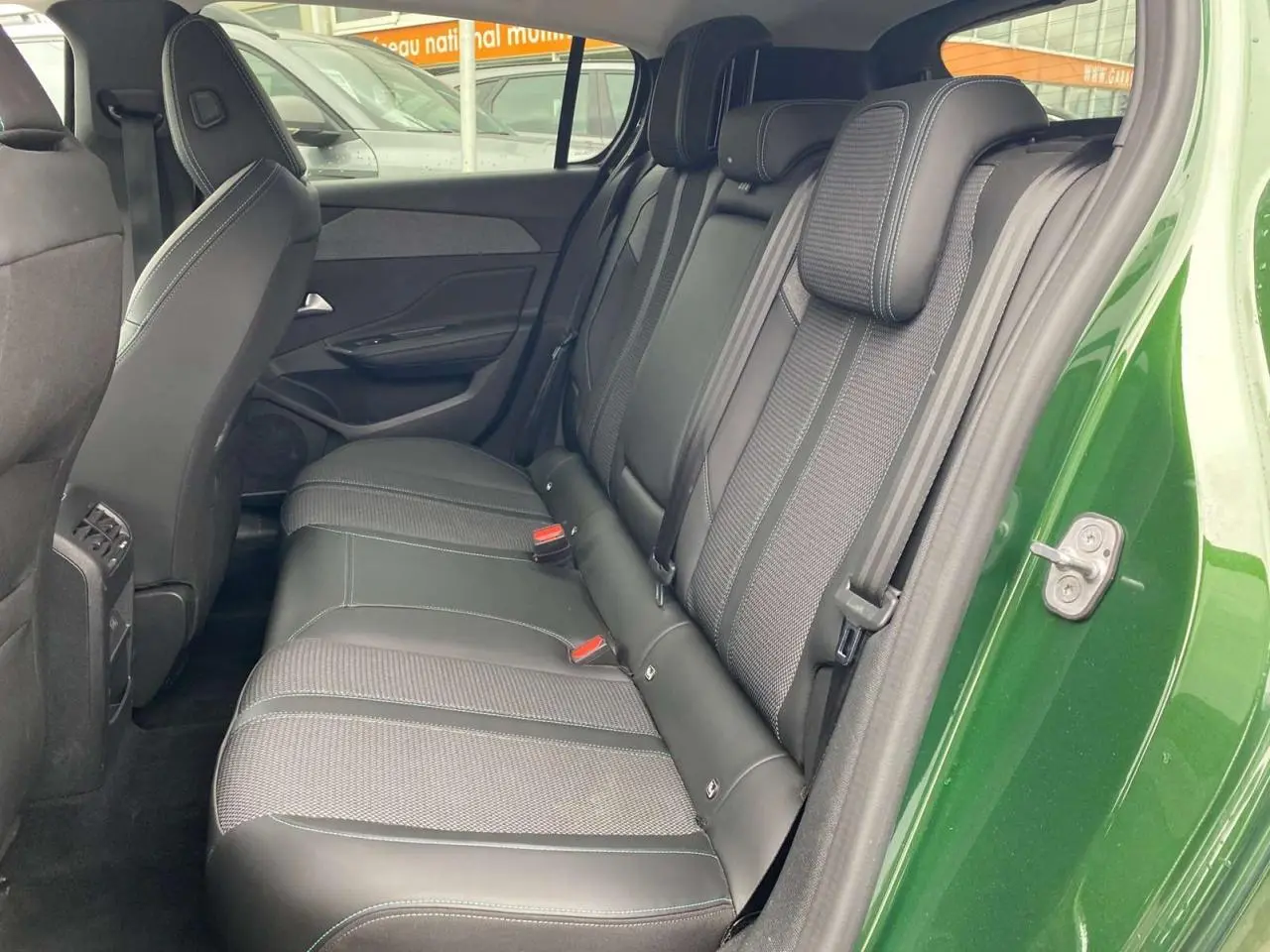 Vue côté gauche de la banquette arrière en cuir noir de la Peugeot 308 2023 vert olivine avec porte ouverte.