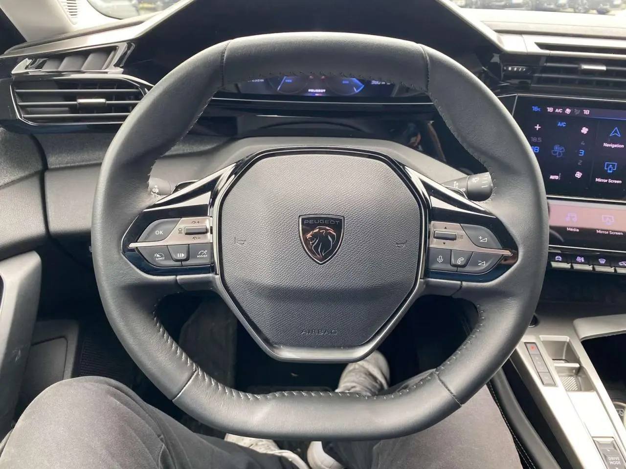 Volant cuir noir de Peugeot 308 2023 vu de face, avec commandes intégrées et tableau de bord numérique bleu.