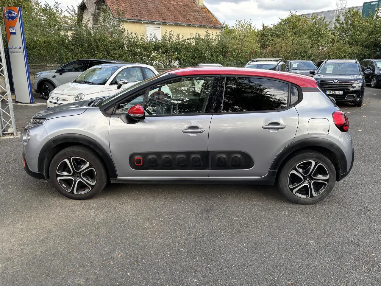 Profil côté gauche d'une Citroën C3 gris clair avec toit rouge et Airbump noir à détail rouge sur porte avant.