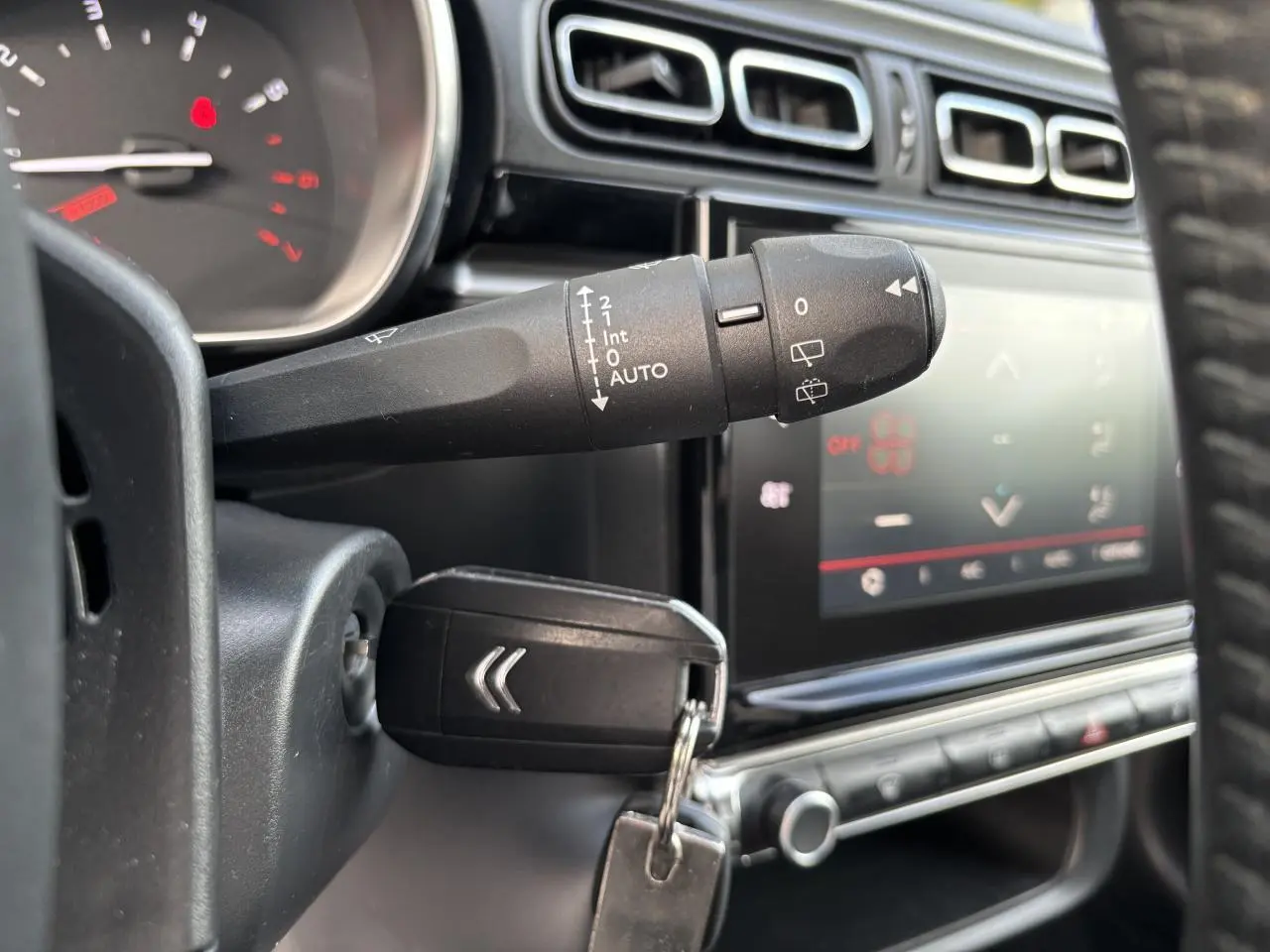 Gros plan sur la commande d'essuie-glace et clé insérée dans le contacteur d'une Citroën C3 2019, intérieur noir.