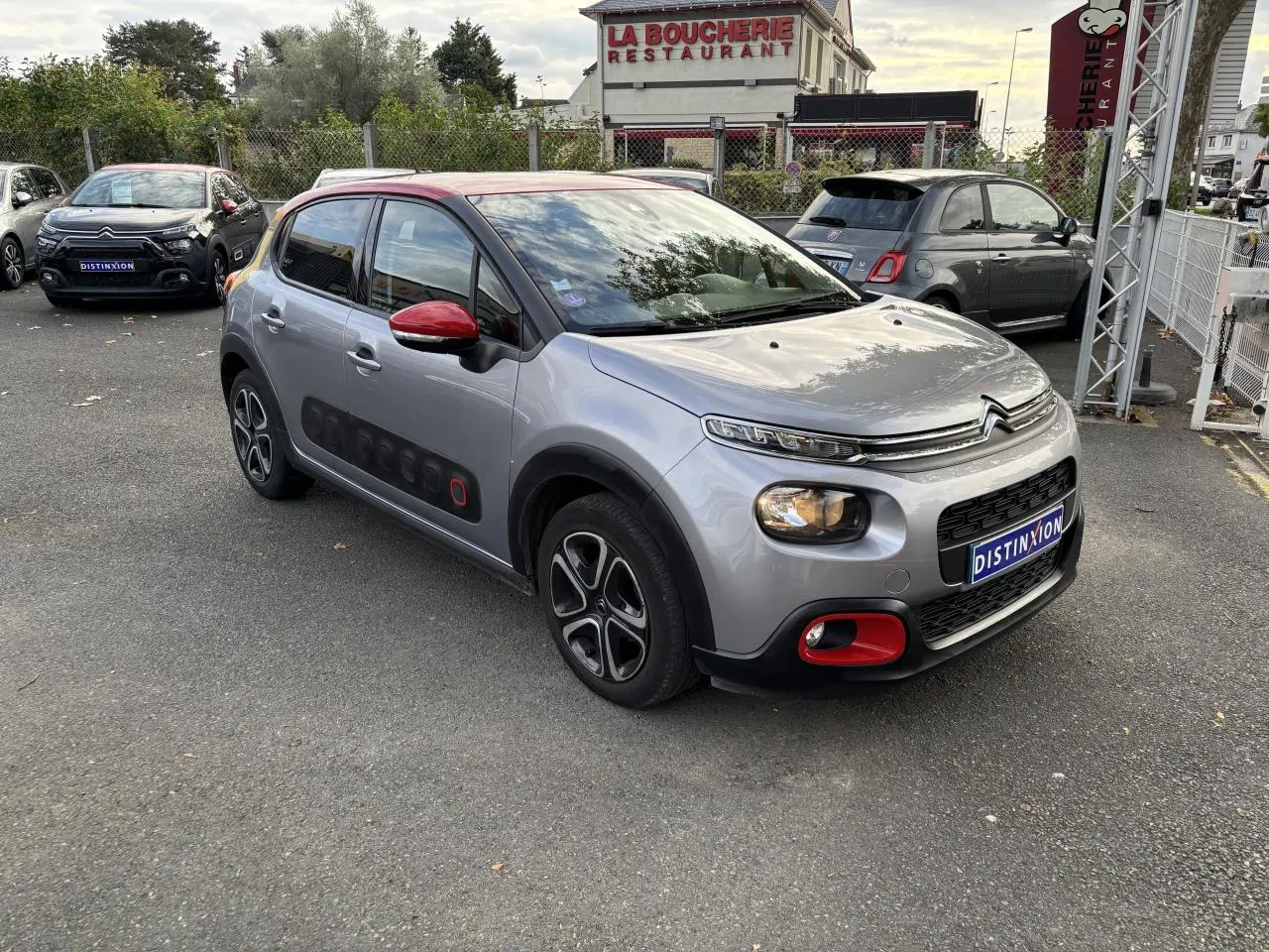 Citroën C3 gris à toit rouge en 3/4 avant droit, avec Airbump noir et accents rouges sur pare-chocs et rétroviseur.