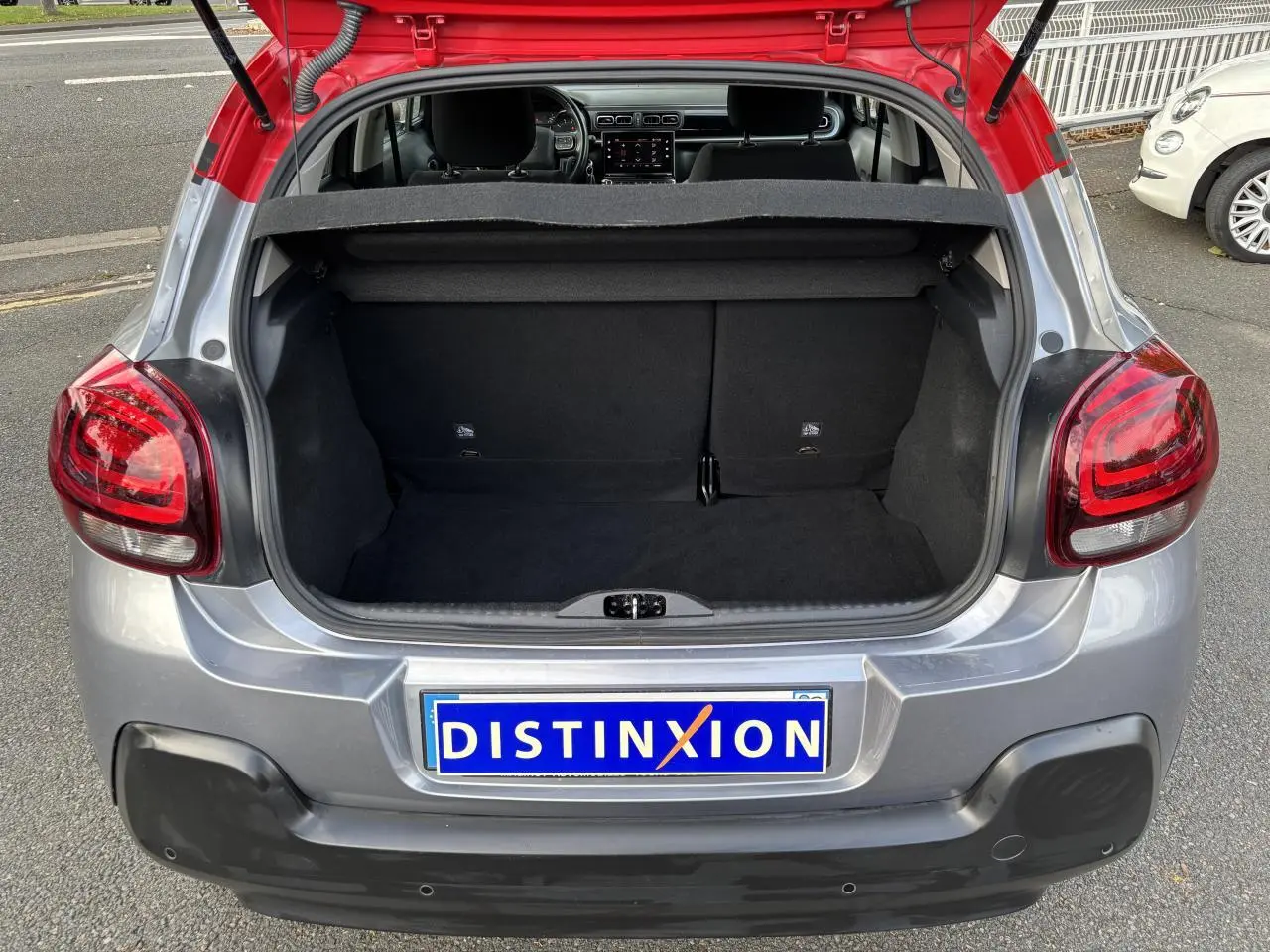 Coffre ouvert d'une Citroën C3 2019 gris avec toit rouge, vue arrière mettant en valeur les feux et le hayon.