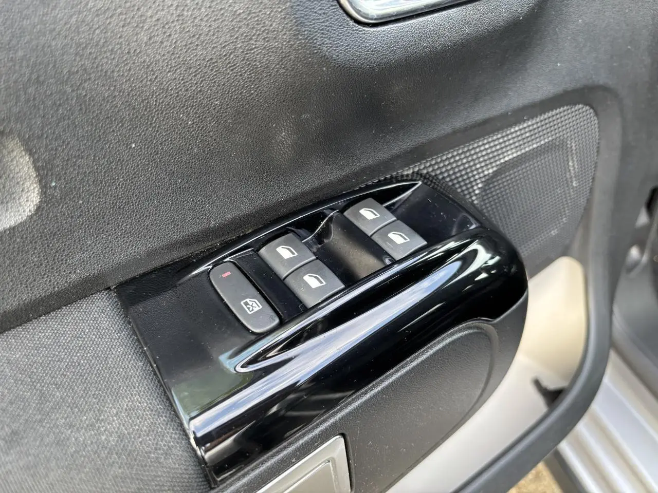 Gros plan sur les commandes des lève-vitres côté conducteur d'une Citroën C3 2019 gris avec toit rouge.