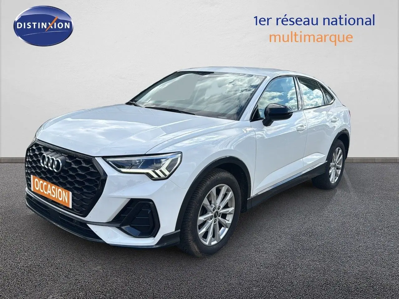 Audi Q3 Sportback blanc en 3/4 avant droit, avec calandre noire et feux LED distinctifs visibles.