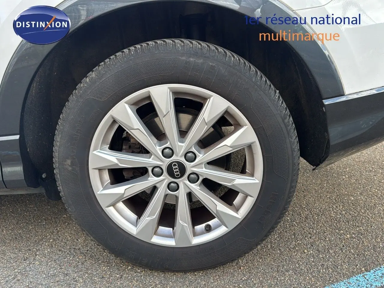 Gros plan sur la roue avant gauche de l'Audi Q3 Sportback blanc avec jante alliage 18 pouces au design moderne.