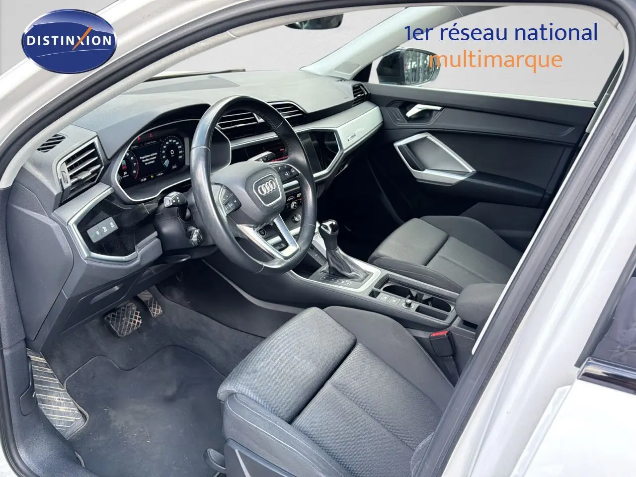 Intérieur noir de l'Audi Q3 Sportback blanc 2021, vue côté conducteur avec tableau de bord et console centrale visibles.