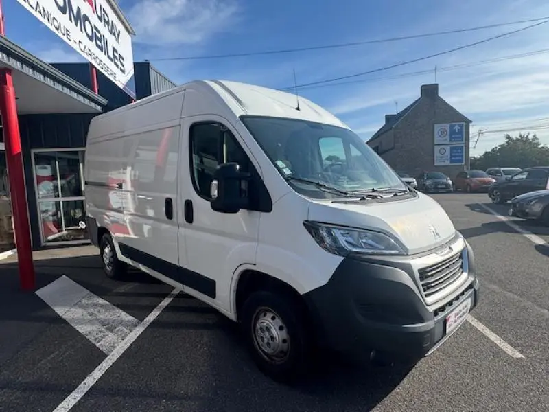 Peugeot Boxer Fourgon blanc Banquise vu en 3/4 avant droit sur parking devant un garage.