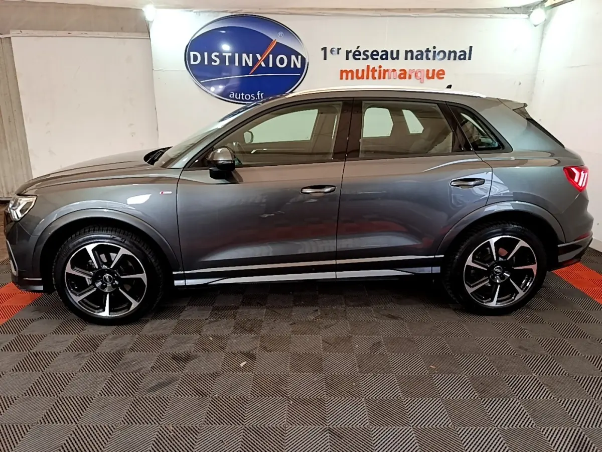 Vue latérale droite d’un Audi Q3 gris foncé 35 TFSI S LINE avec jantes noires et feux arrière allumés.
