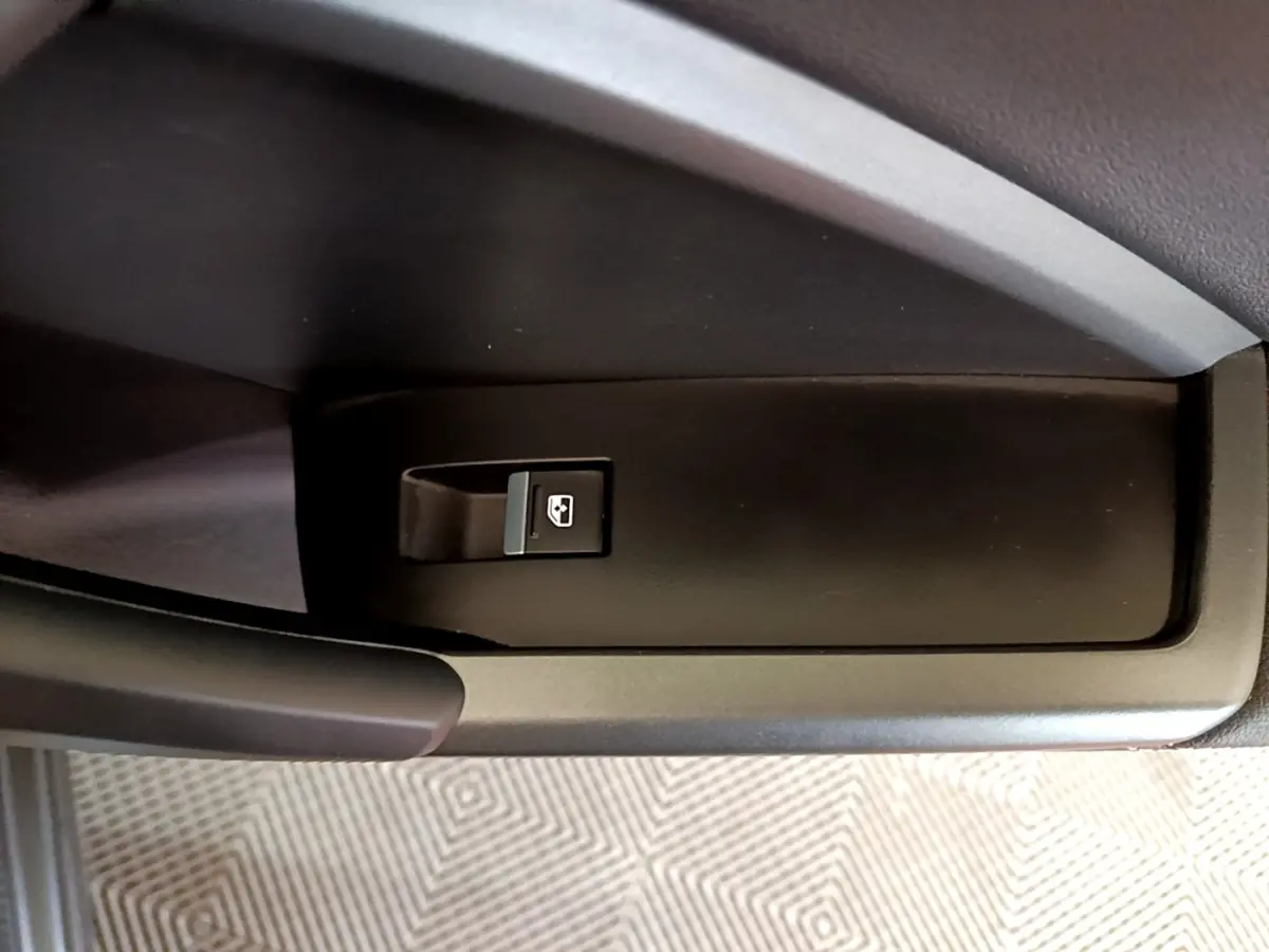 Gros plan sur le bouton de commande de la vitre électrique côté conducteur dans l'habitacle noir de l'Audi Q3 gris foncé.