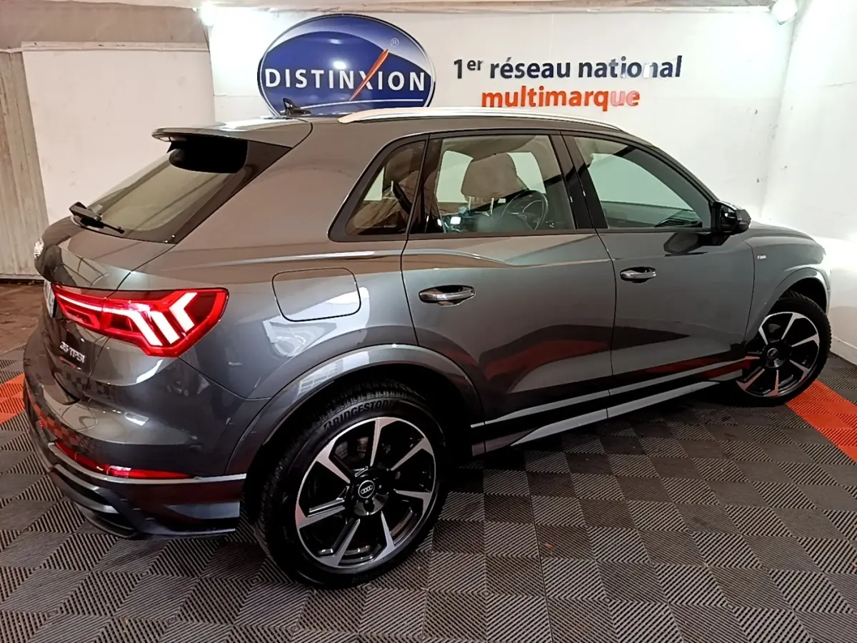 Audi Q3 35 TFSI S Line gris foncé vue 3/4 arrière droit, feux LED allumés et jantes noires distinctives.