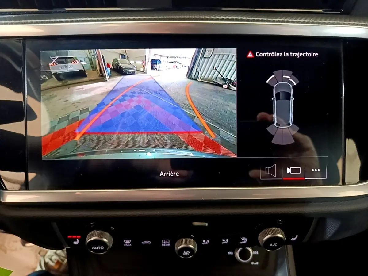 Écran tactile intérieur montrant la caméra de recul et l'aide au stationnement du tableau de bord d'un Audi Q3 gris foncé.