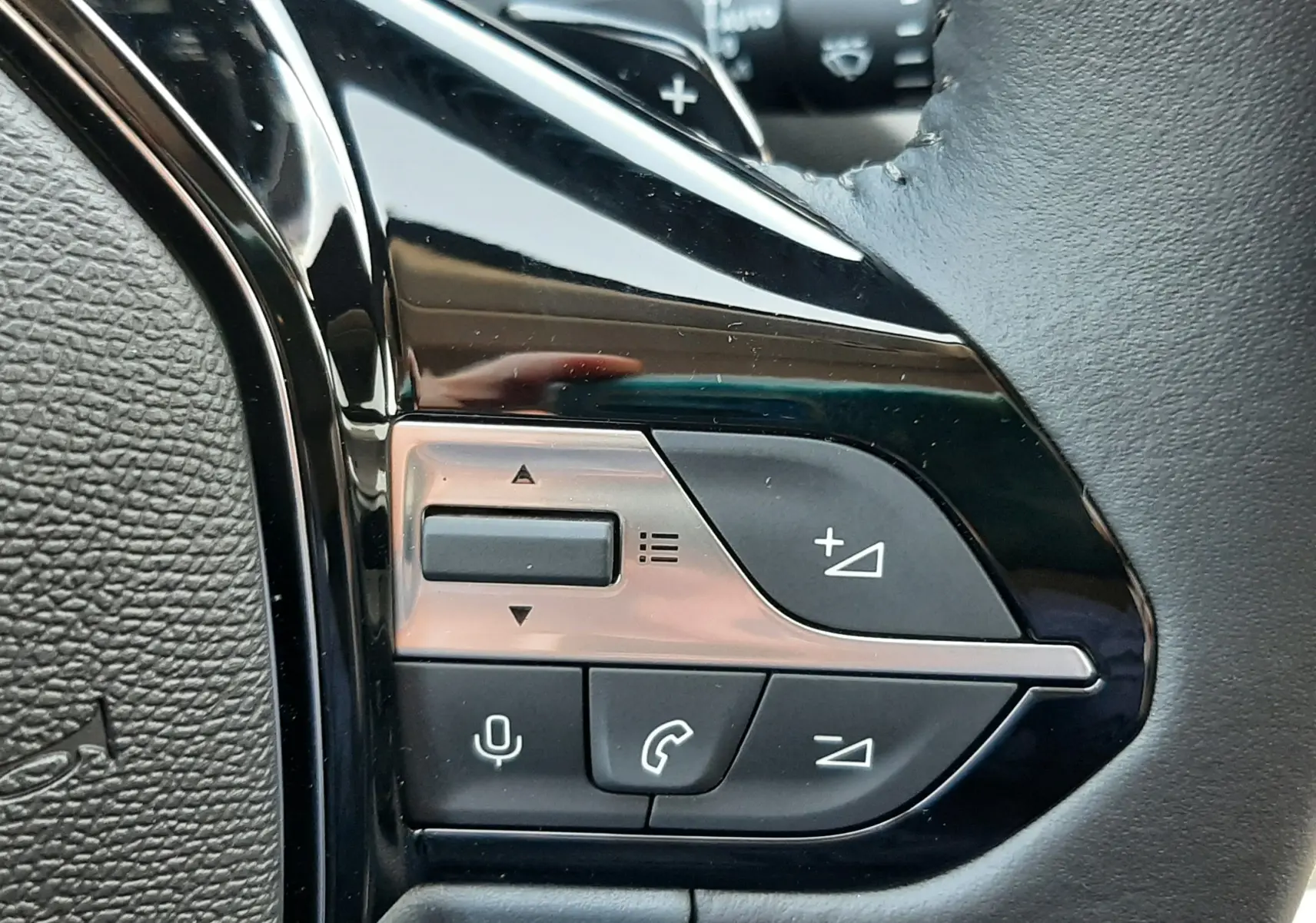 Gros plan sur les commandes de régulateur de vitesse au volant noir de la Peugeot 308 Bleu Obsession 2026.