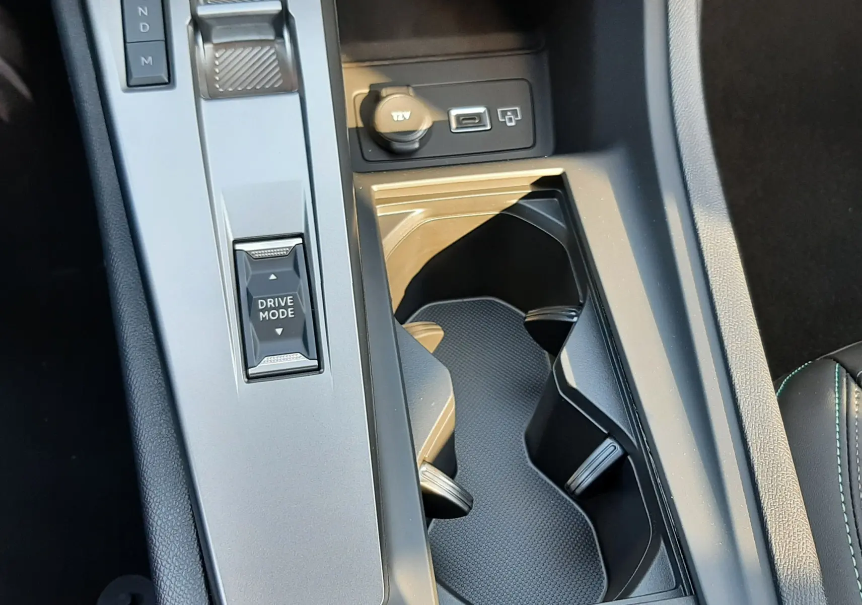 Gros plan sur la console centrale de la Peugeot 308 2026, avec levier de boîte auto, bouton Drive Mode et prise 12V visible.
