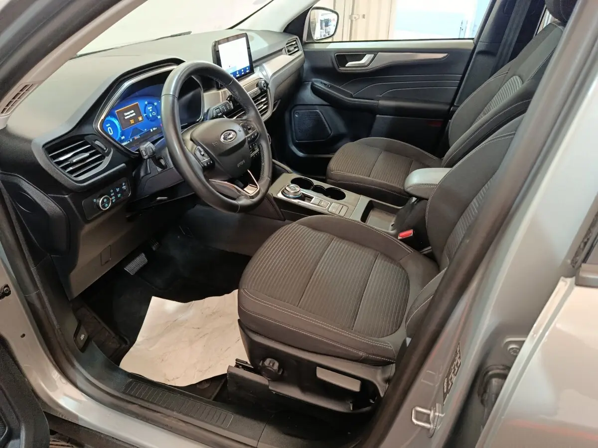 Vue intérieure côté conducteur du Ford Kuga gris foncé 2023, avec tableau de bord numérique et volant multifonctions cuir.