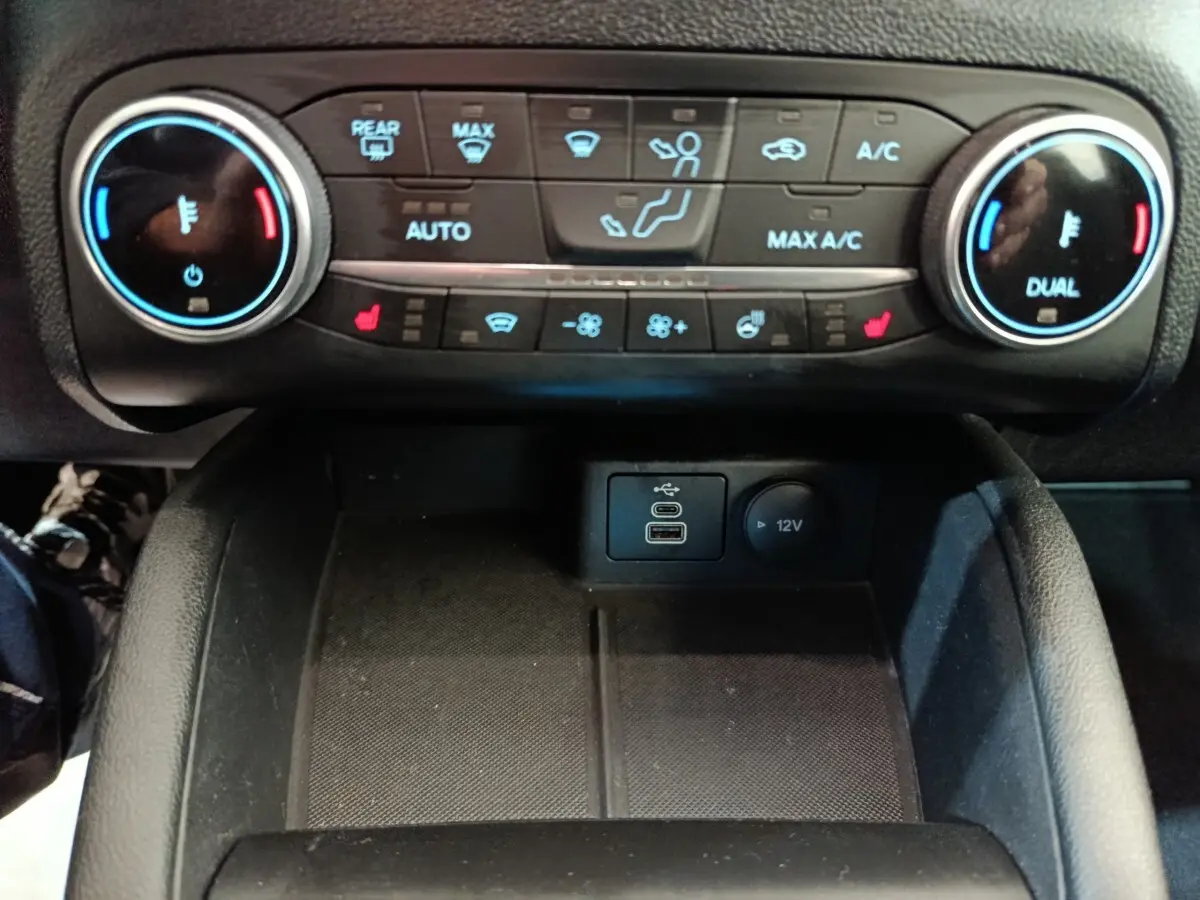 Vue rapprochée du tableau de bord central du Ford Kuga 2023, montrant les commandes de climatisation et ports USB.
