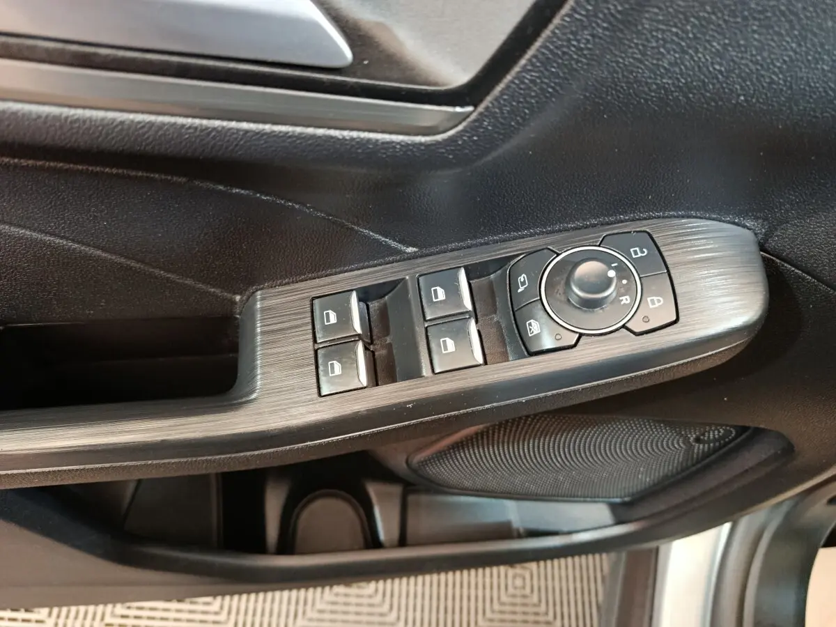 Gros plan sur la commande des vitres et rétroviseurs côté conducteur du Ford Kuga gris foncé 2023.