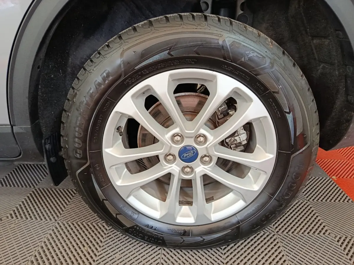 Gros plan sur la roue avant droite d’un Ford Kuga gris foncé, avec jante alliage et pneu Goodyear visible.