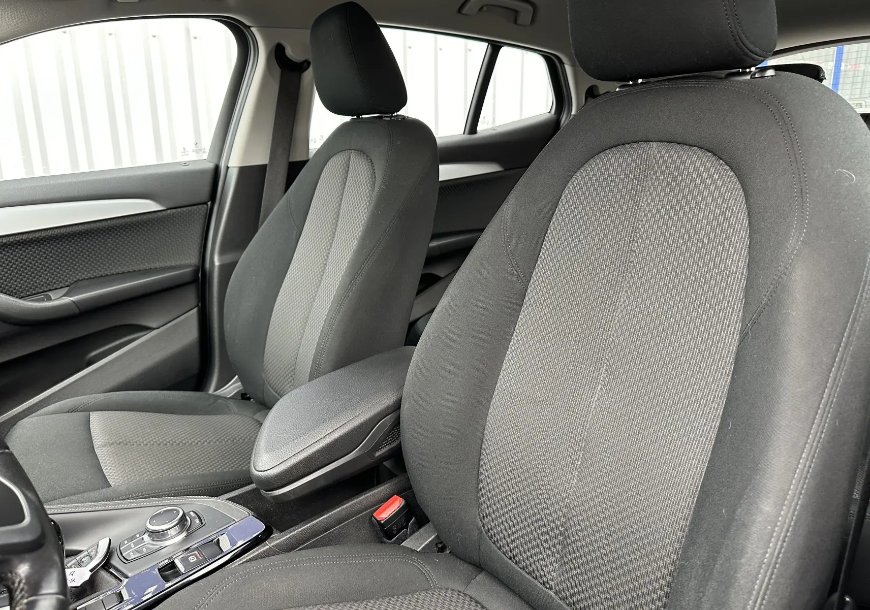 Intérieur avant du BMW X2 gris 2018, vue côté droit sur les sièges tissu et la console centrale.