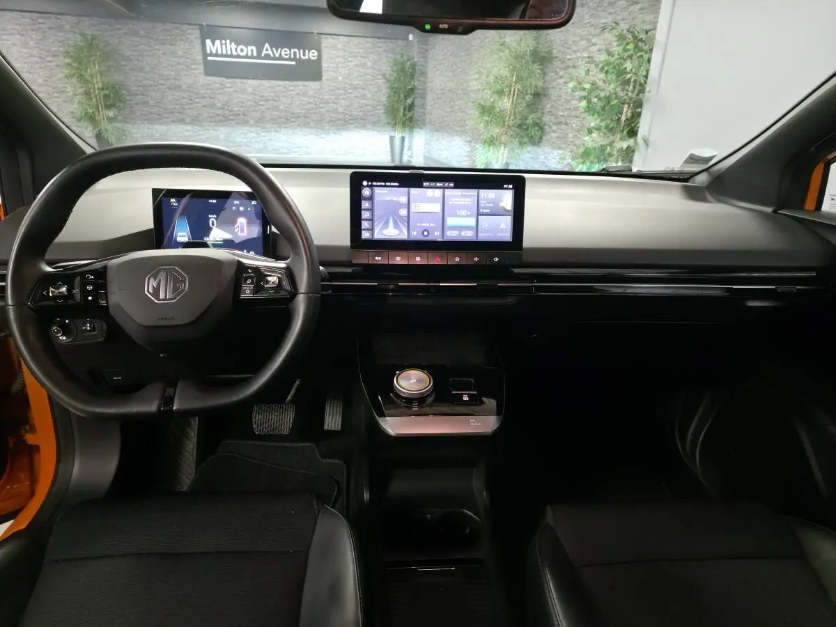 Intérieur du MG4 orange vu de face, tableau de bord moderne avec écran tactile central et volant multifonction noir.