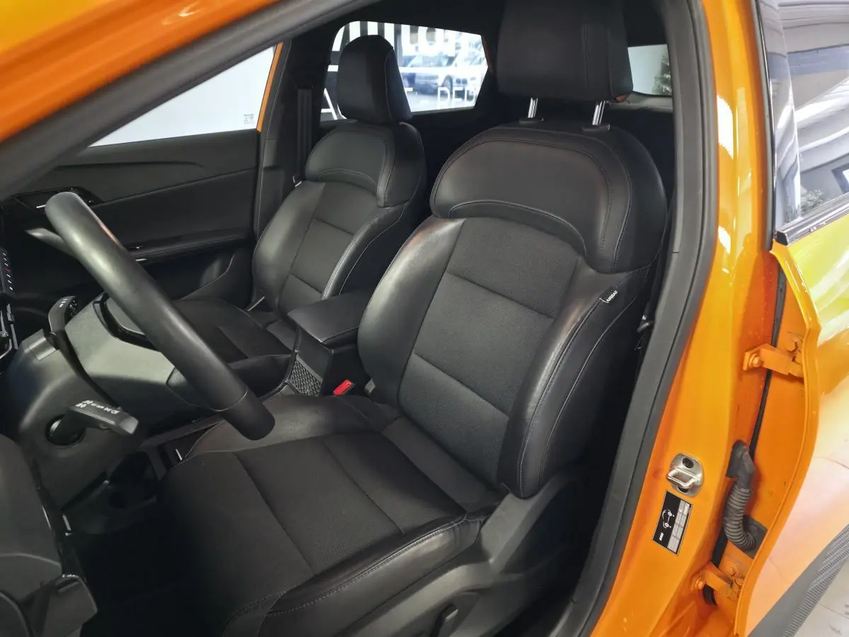 Vue intérieure côté conducteur du MG4 orange 2022, mettant en valeur les sièges noirs en tissu et similicuir et le volant cuir.