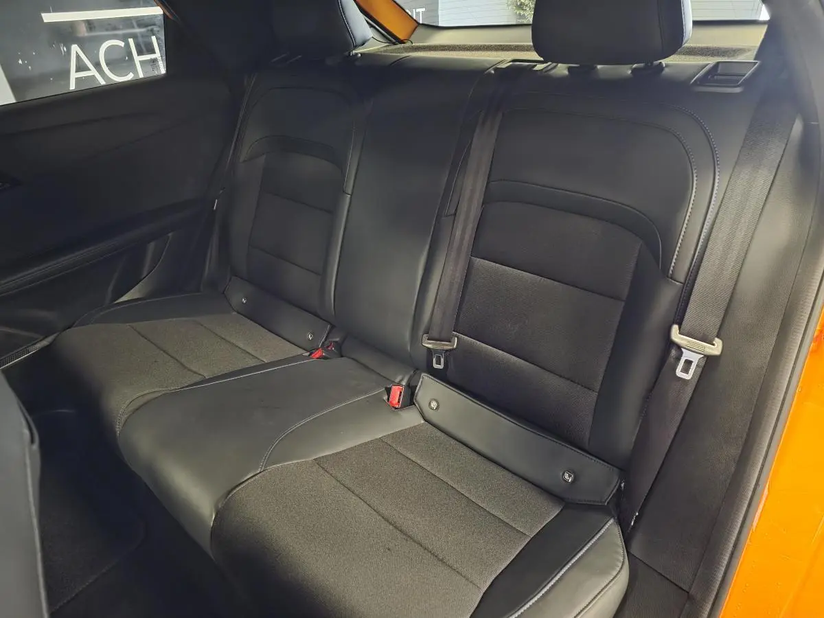 Vue intérieure de la banquette arrière noire en tissu et similicuir du MG4 orange, avec ceintures de sécurité visibles.