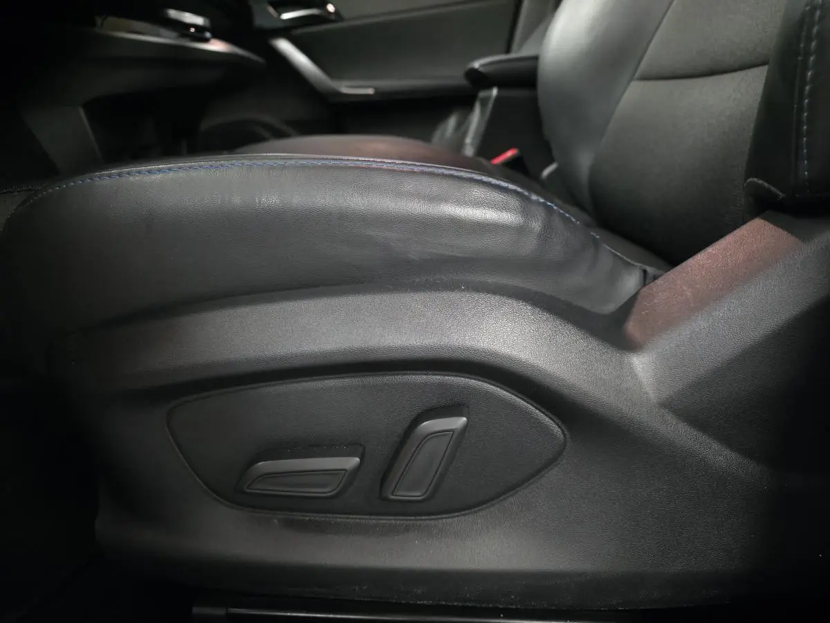 Gros plan sur les commandes électriques du siège conducteur en cuir noir de la MG4 Luxury 2022, intérieur sombre.