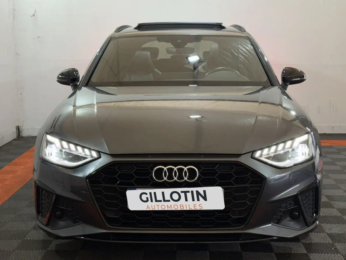 Audi A4 35 TFSI S Edition gris foncé vue de face avec phares LED allumés et calandre noire hexagonale.