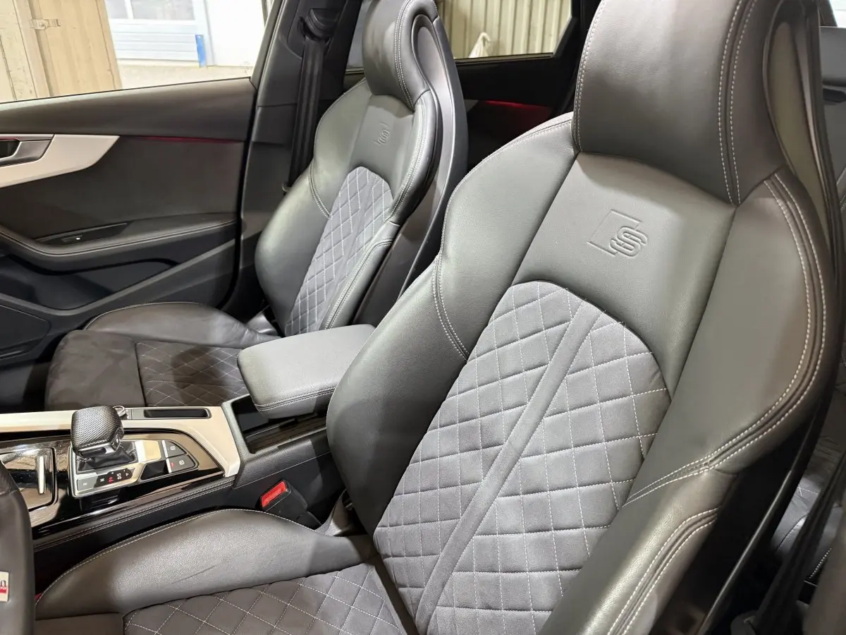 Vue intérieure rapprochée des sièges avant en cuir noir et tissu gris avec logo S embossé sur un Audi A4 35 TFSI 2022.