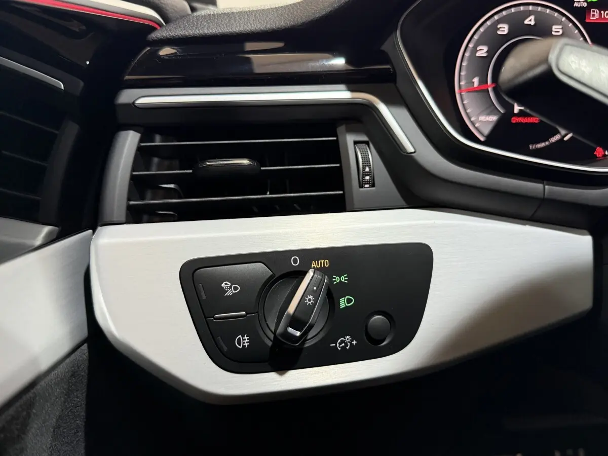 Détail du tableau de bord côté gauche d'une Audi A4 gris foncé 2022 avec commande d'éclairage en mode auto.