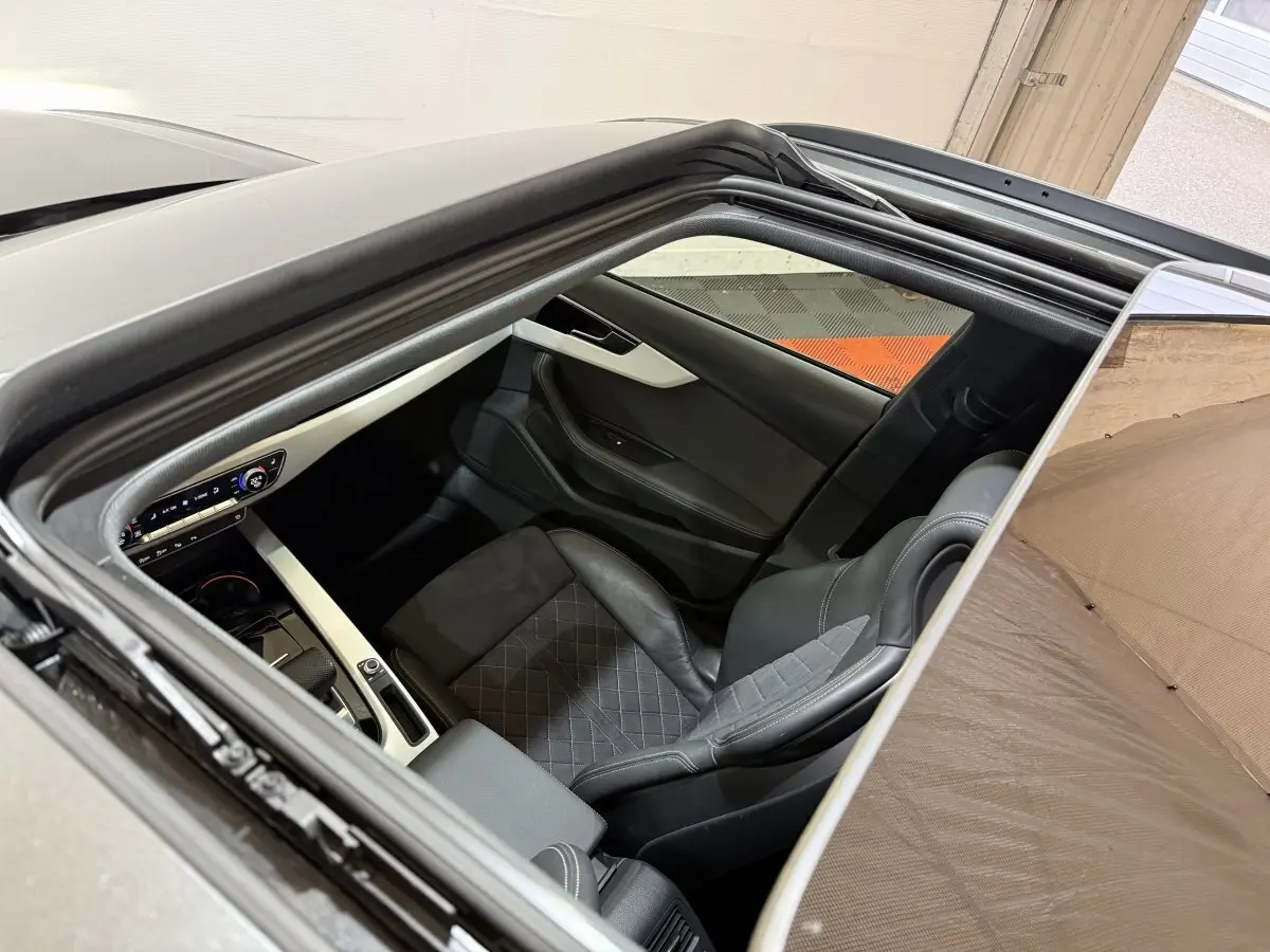 Vue plongeante par le toit ouvrant sur l'intérieur noir et gris de l'Audi A4 35 TFSI S Edition 2022.