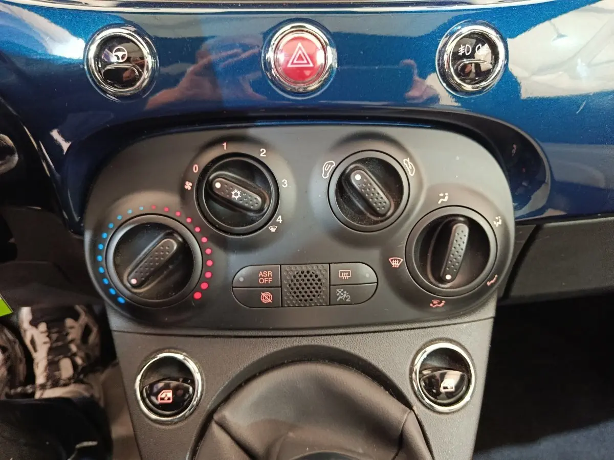 Vue rapprochée du tableau de bord bleu de la Fiat 500 Dolcevita 2022, montrant les commandes de climatisation et boutons centraux.