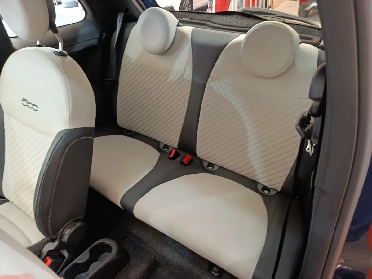 Vue intérieure arrière montrant la banquette beige et noire de la Fiat 500 Hybrid 2022 avec appuie-têtes ronds.