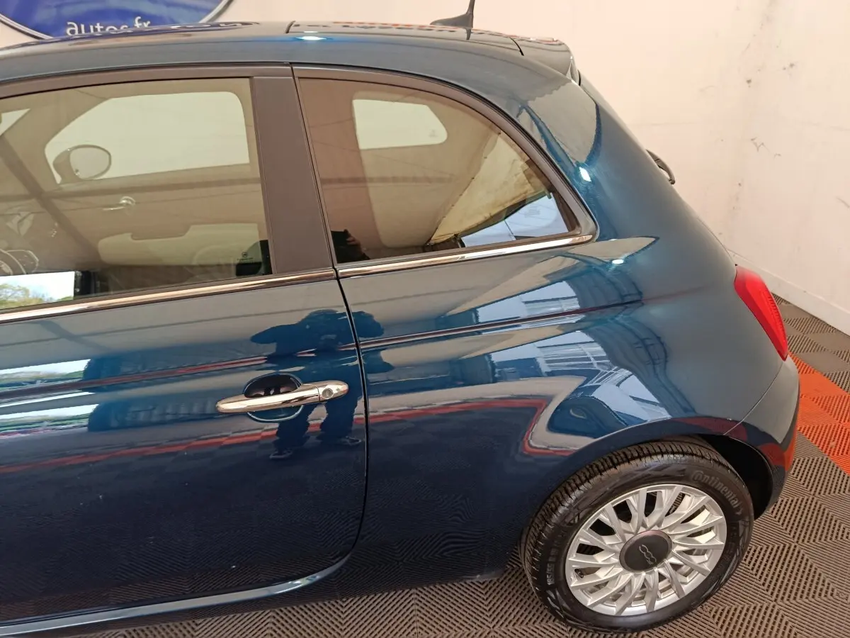 Vue latérale côté droit d'une FIAT 500 Hybrid bleu métallisé avec jante alliage et poignée chromée.