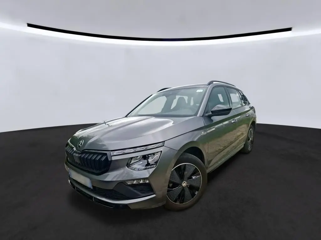 Vue 3/4 avant droit d’un Skoda Kamiq 1.5 TSI 150 DSG7 Monte-Carlo gris foncé avec jantes noires distinctives.
