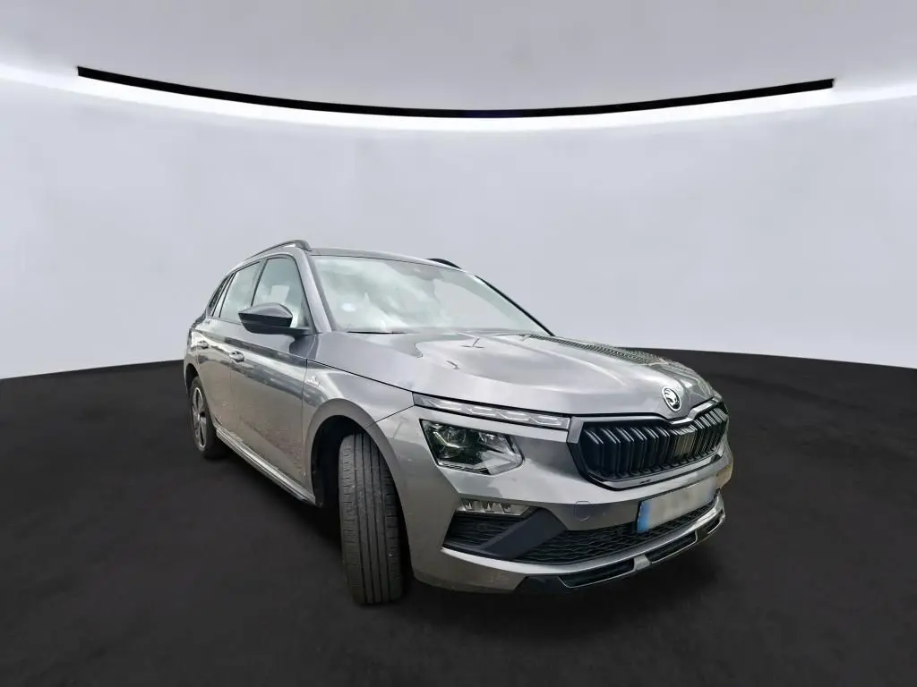 Vue 3/4 avant gauche d’un Skoda Kamiq gris foncé 2024 avec calandre noire et phares LED distinctifs.