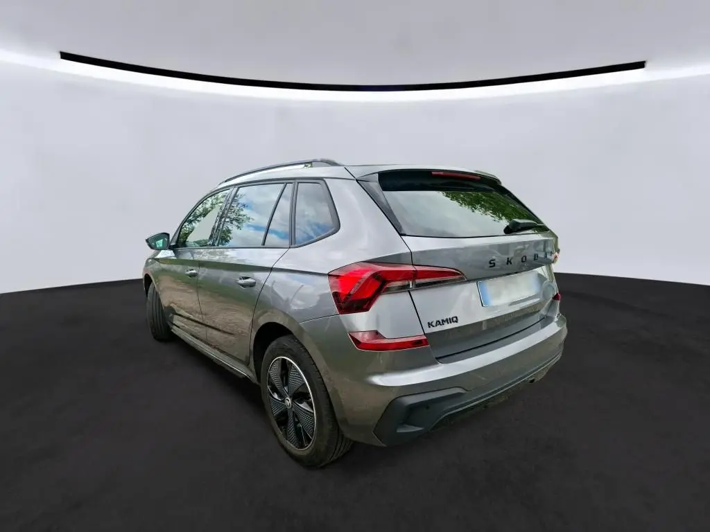 Vue 3/4 arrière gauche d’un Skoda Kamiq gris foncé 2024 avec feux arrière LED et jantes alliage noires.
